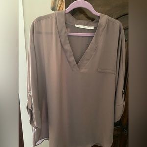 100% polyester Taupe top. Easy to dress up with a scarf or great with jeans.